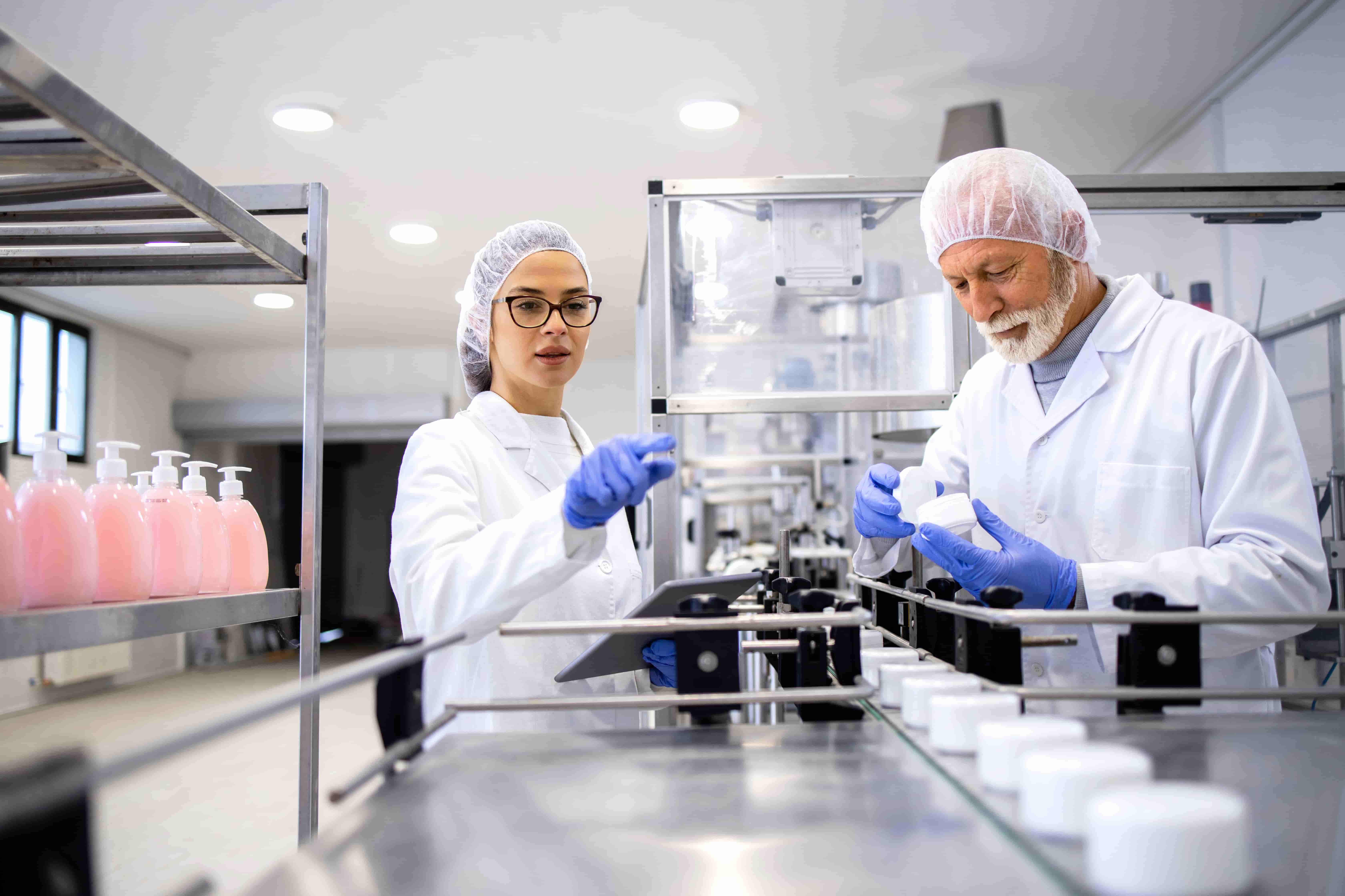 Mitarbeitende in Labor- oder Produktionsumgebung tragen Haarnetz und Schutzhandschuhe für hygienisches Arbeiten