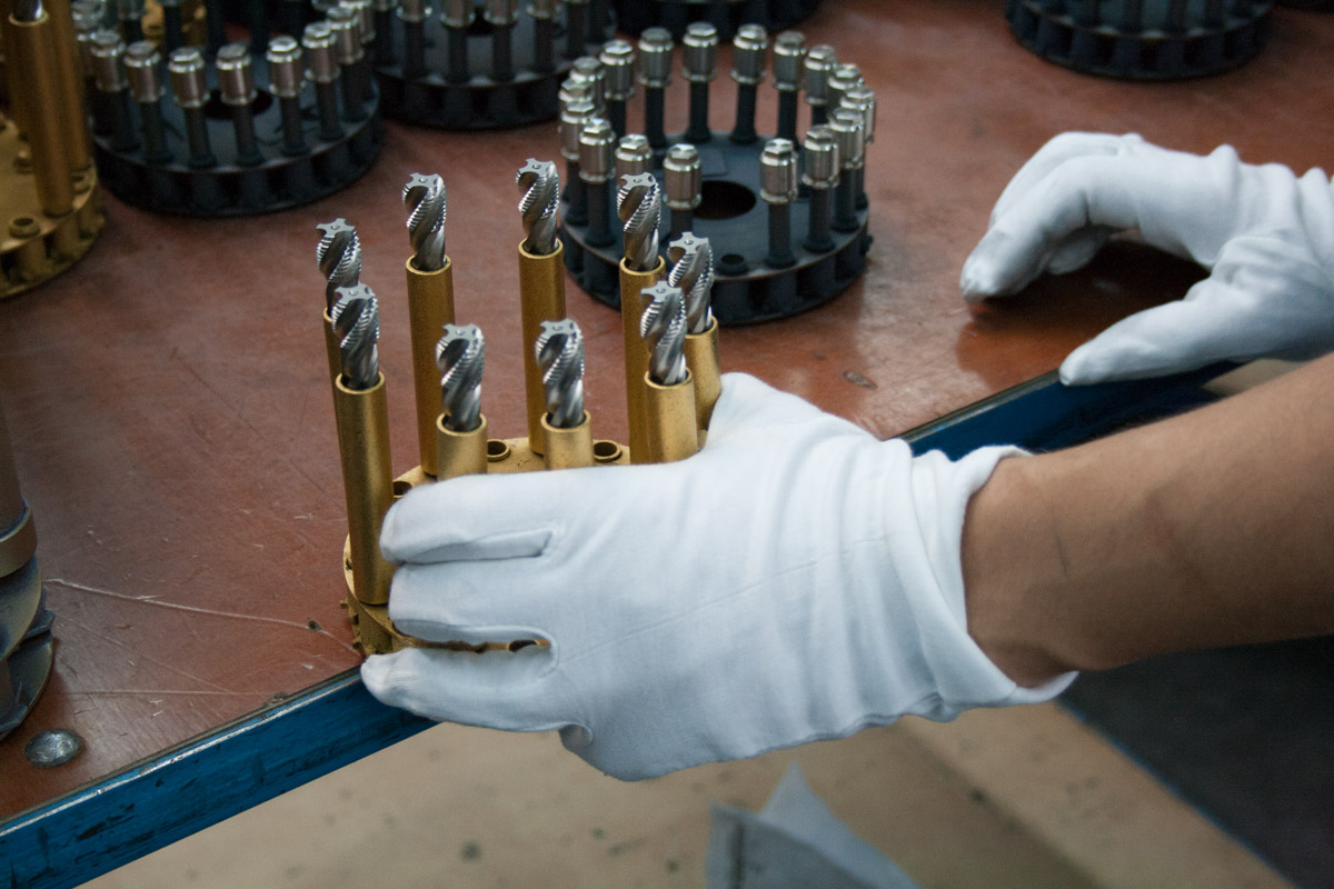 Weiße Baumwollhandschuhe greifen präzise Werkzeuge in einer industriellen Arbeitsumgebung